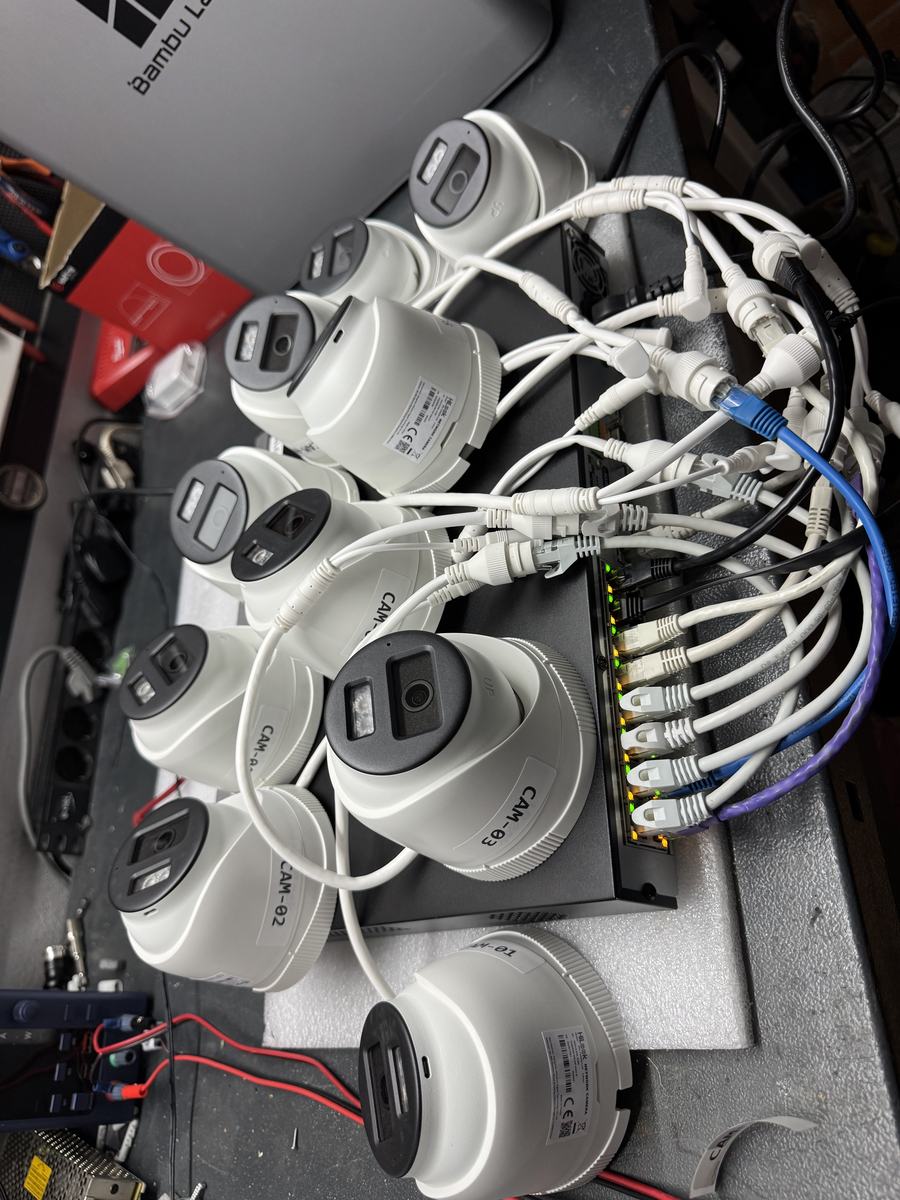 Cámaras domo etiquetadas y conectadas a un switch PoE en el banco de pruebas de BAIOT, listas para configurar antes de la instalación