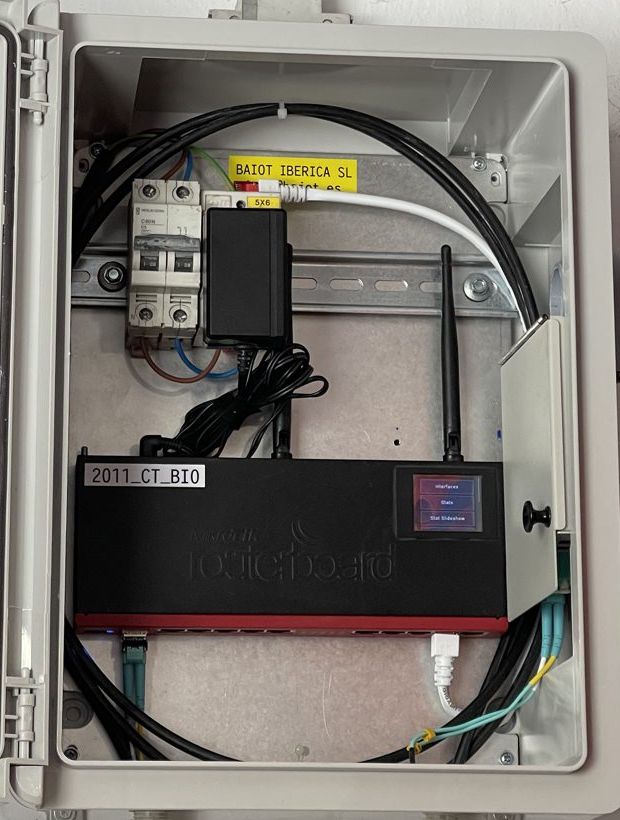 Interior de una caja estanca con router MikroTik y protección eléctrica para contadores telemáticos