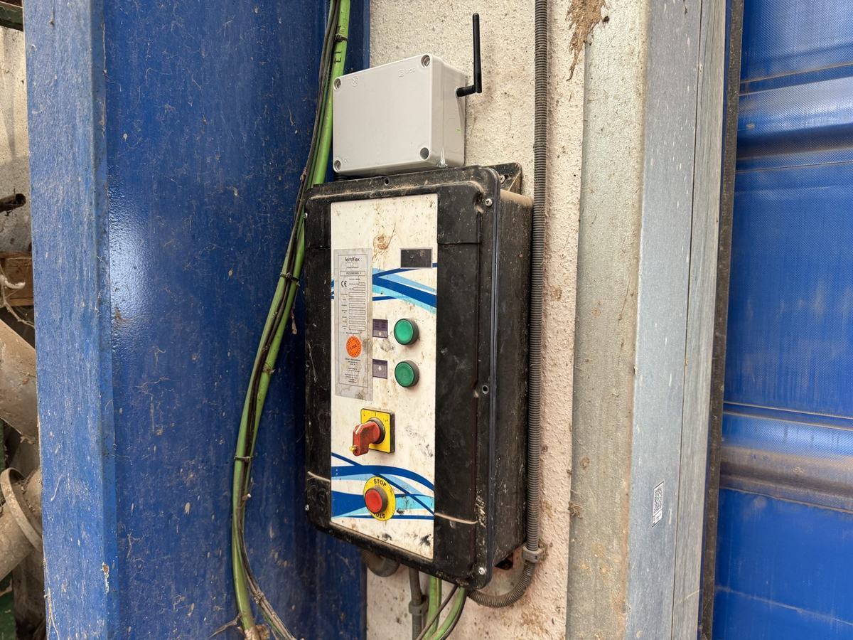 Nodo LoRaWAN con antena instalado sobre el cuadro de mando de una puerta industrial