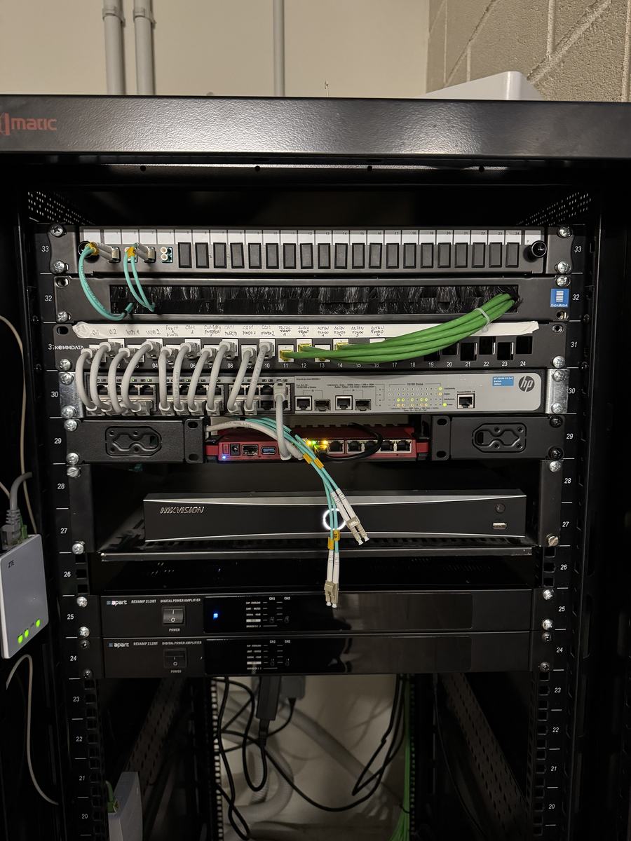 Rack de una de las naves con patch panel, switch HP, grabador Hikvision y latiguillos de fibra